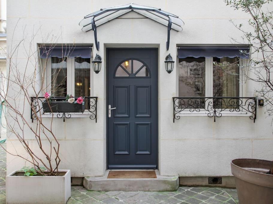 une maison avec une porte bleue et deux fenêtres dans l'établissement La Villa du Louvre, à Paris