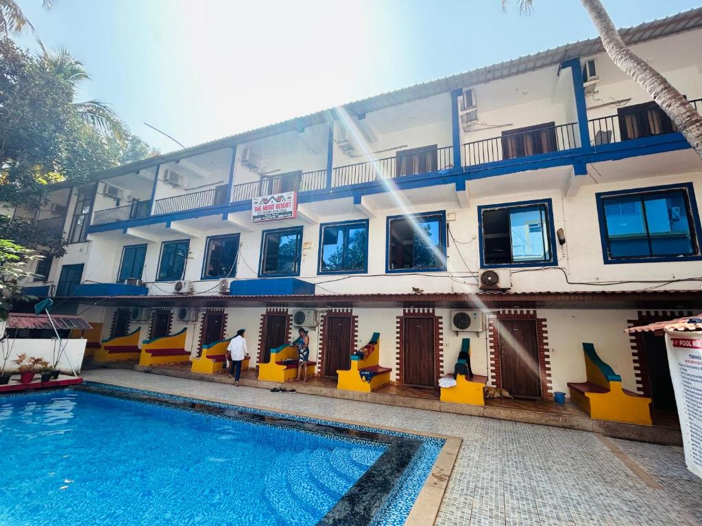 a hotel with a swimming pool in front of a building at The merit resort in Arpora