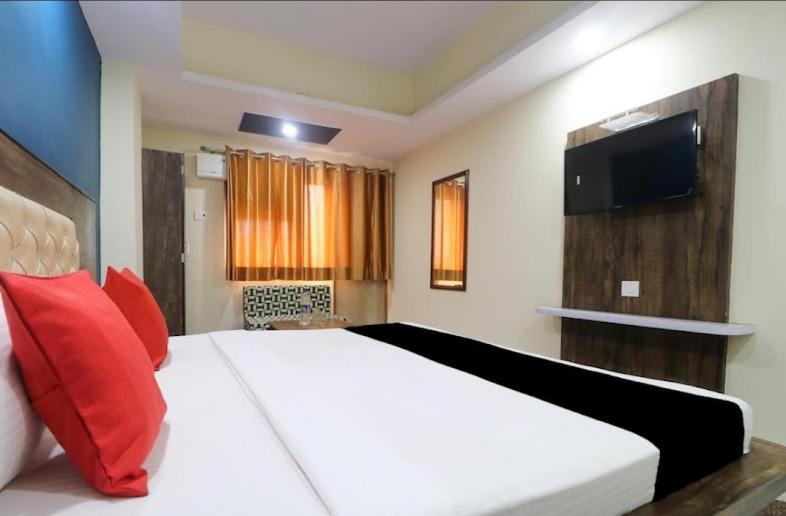 hotel nanda inn في حاريدوار: غرفة نوم مع سرير أبيض كبير مع وسائد حمراء