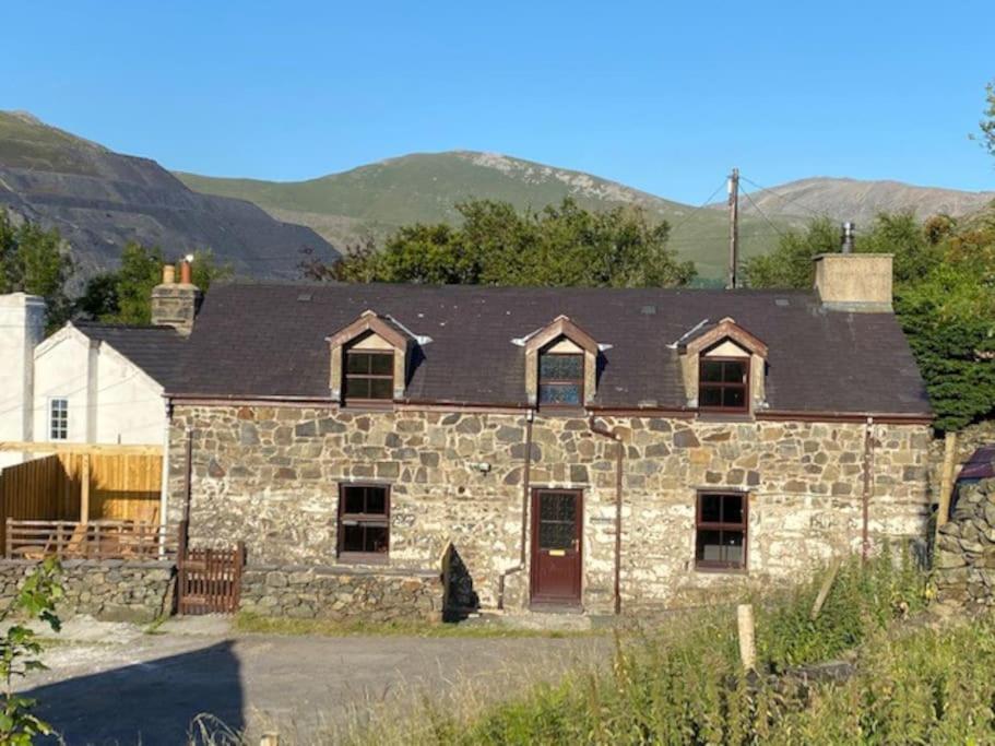 Traditional Welsh cottage in Llanberis في لانبيريس: منزل حجري قديم بسقف أسود