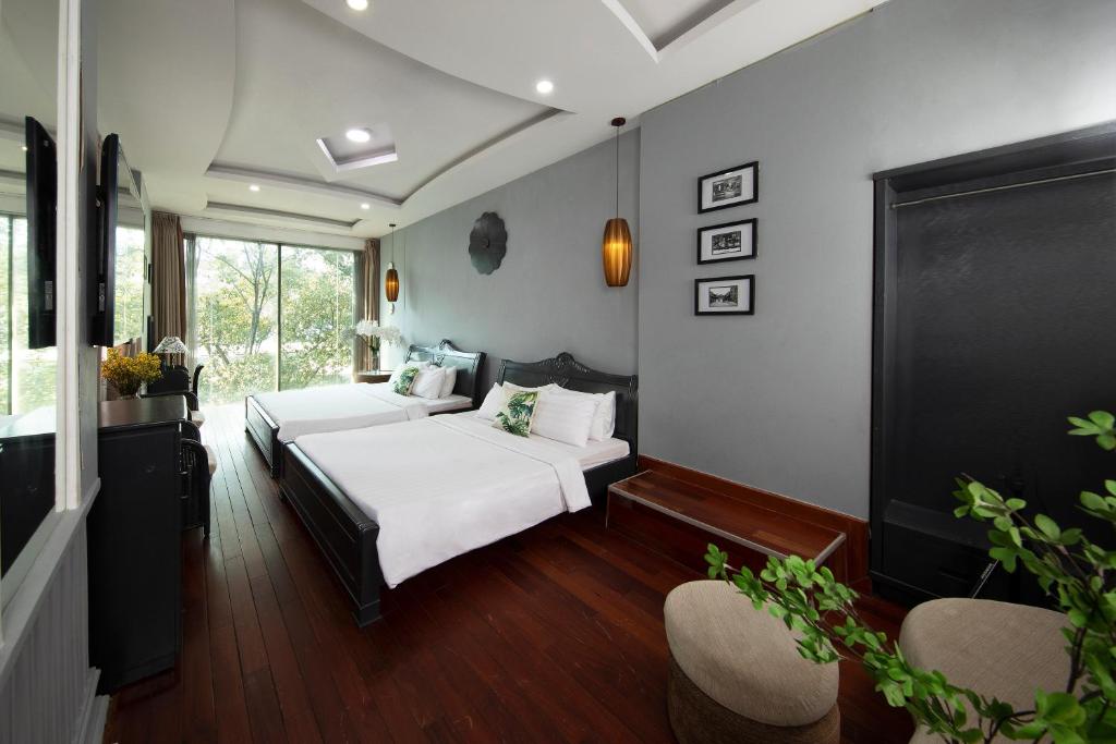 a bedroom with two beds and two chairs at Vintage Boutique Hotel & Spa in Ho Chi Minh City