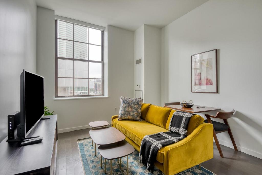 uma sala de estar com um sofá amarelo e uma televisão em Downtown studio w gym wd nr waterfront BOS-985 em Boston