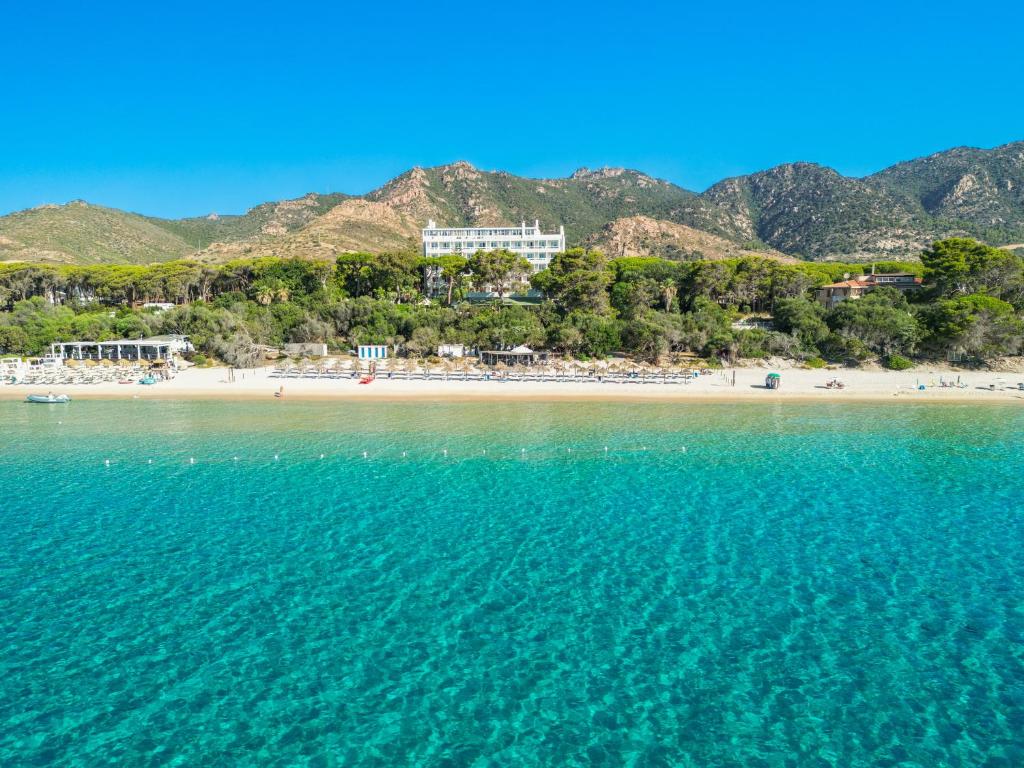a view of a beach with mountains in the background at Abamar Hotel in Santa Margherita di Pula