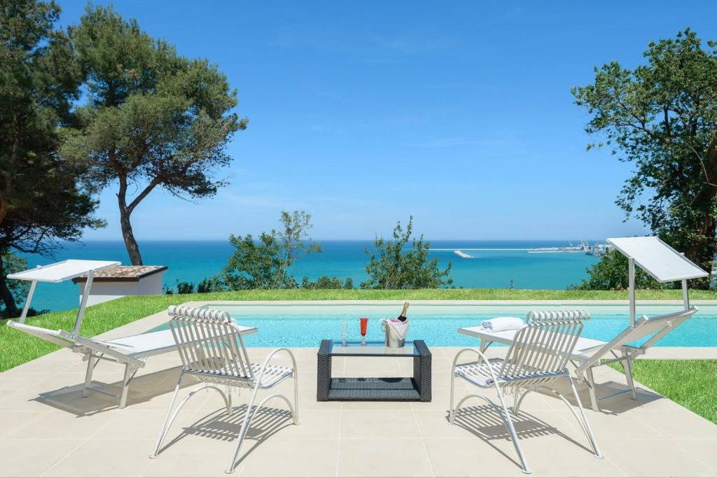 安科納的住宿－Italian Experience- Villa Krizia，一个带两把椅子和一张桌子的庭院和一个游泳池