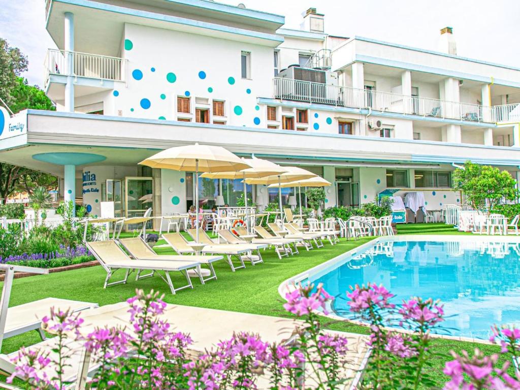 ein Hotel mit einem Pool, Stühlen und Sonnenschirmen in der Unterkunft Family Hotel Alexander in Lido di Jesolo