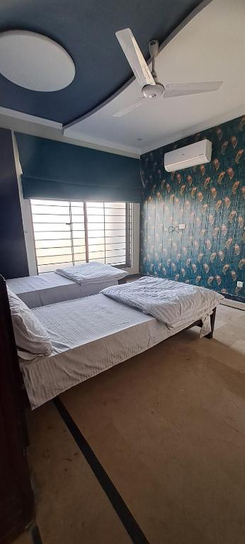 een bed in een kamer met een blauwe muur bij Islamabad Transit Guest House in Islamabad
