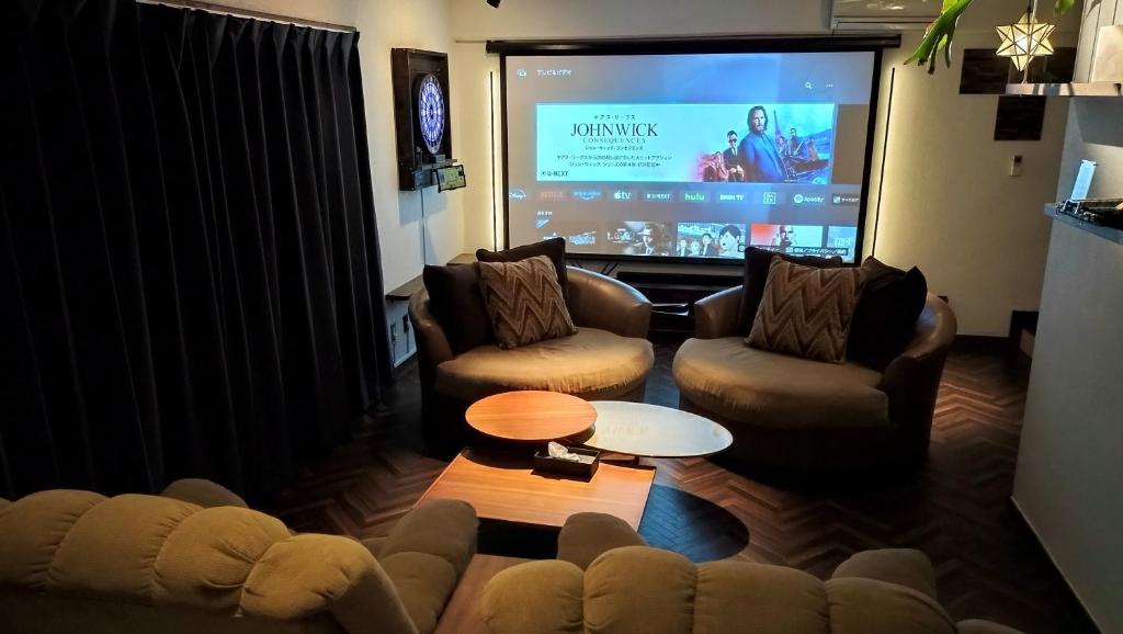 een woonkamer met 2 banken en een groot scherm bij Cinema Resorts 1 in Motobu