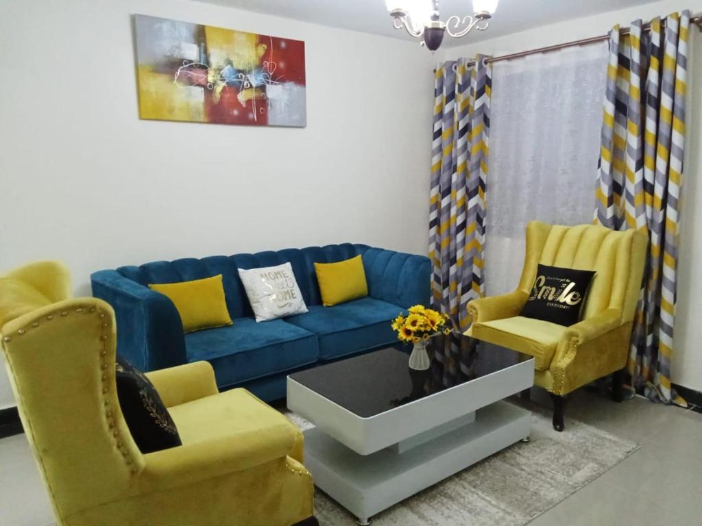 a living room with a blue couch and two yellow chairs at Mellow Homes 1 & 2 Bedrooms fully furnished Apartment in Kitengela 