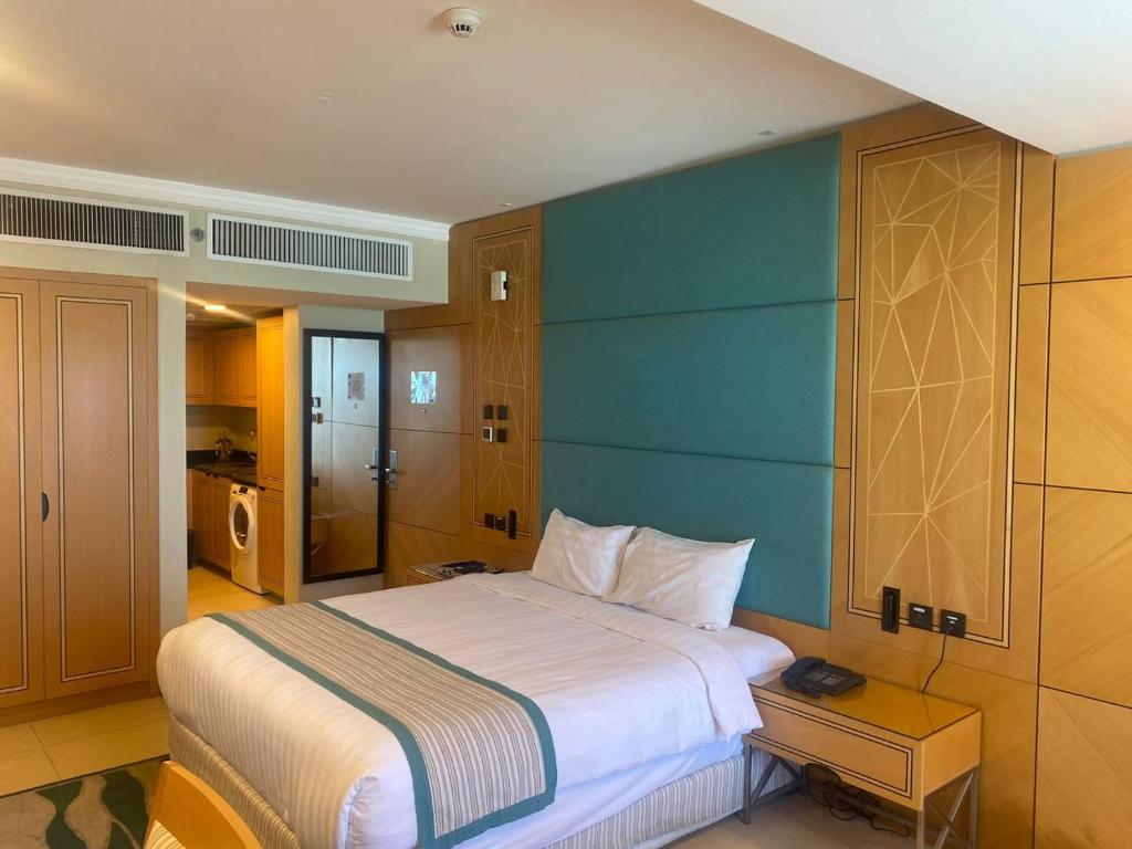 1 dormitorio con 1 cama grande y pared azul en Nooh Apartment, en Al Ḩadd