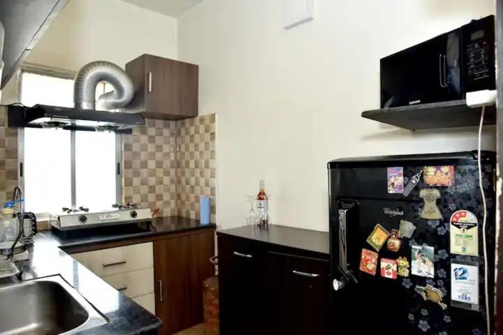 a kitchen with a black refrigerator with magnets on it at Orchid B&B in Kolkata