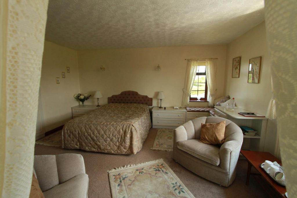 a bedroom with a bed and a couch and a chair at Pointers Guest House in Wistow