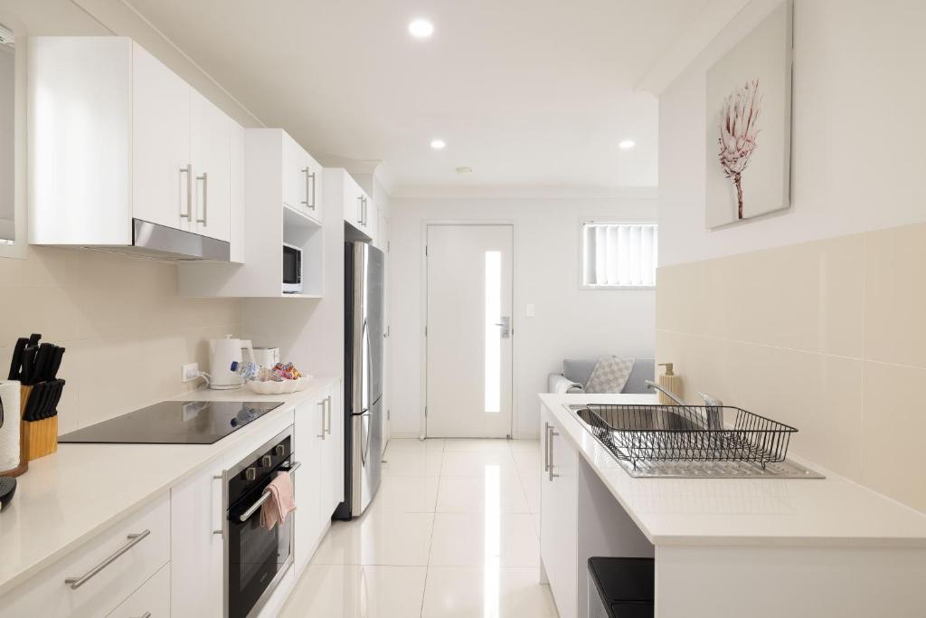 a white kitchen with white counters and appliances at Aircon! Parking! Host with 100s of 5 star Reviews! in Brisbane