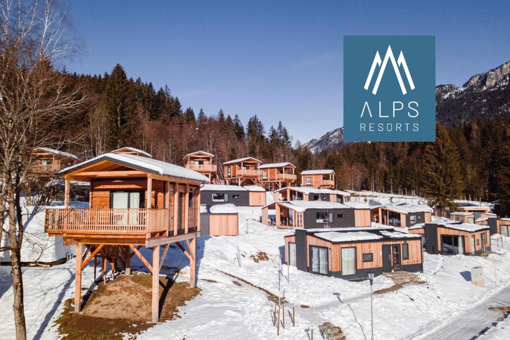 een groep huizen in de sneeuw met een mfs-logo bij Chalets & Glamping Nassfeld by ALPS RESORTS in Kötschach