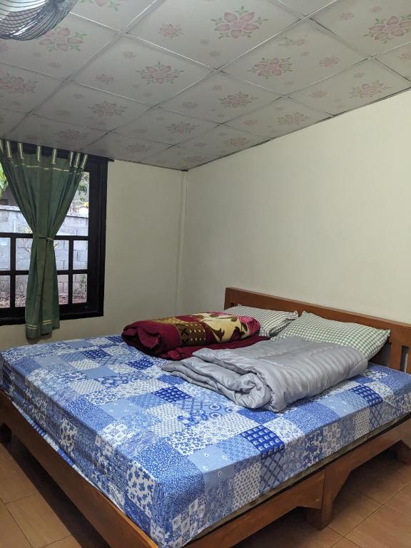 a bedroom with a bed with a blue quilt on it at ที่ราบสูง & โฮมสเตย์ in Ban Mae Na Tai