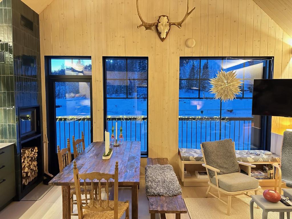 a dining room with a table and chairs and windows at Ljungvind Funäsdalen in Funäsdalen