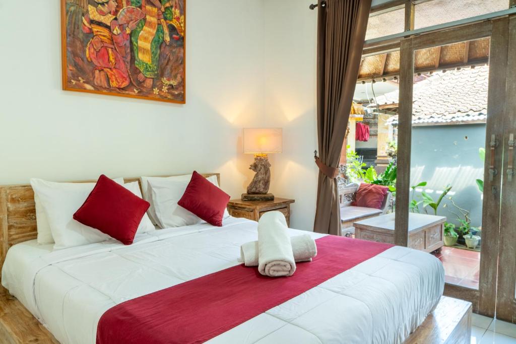 a bedroom with a large white bed with red pillows at Purnama House in Ubud