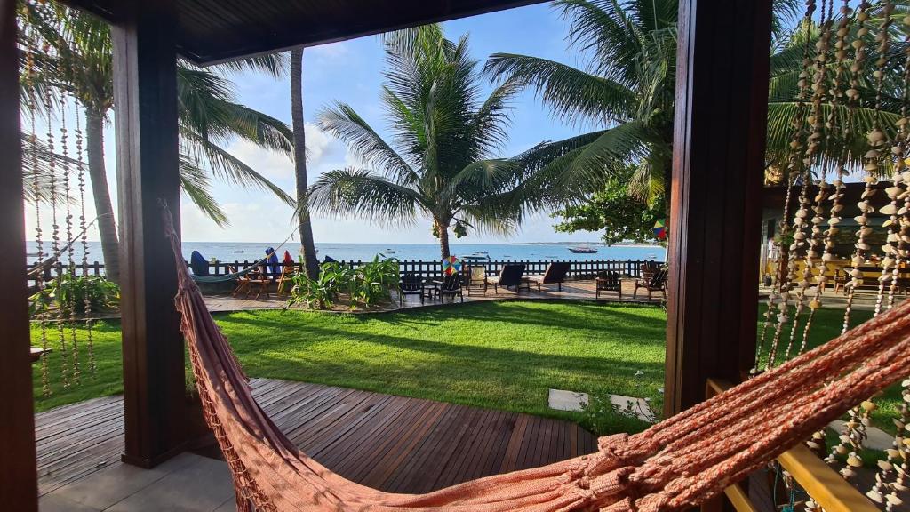 a hammock on a porch with a view of the ocean at Kaapalua in Porto De Galinhas