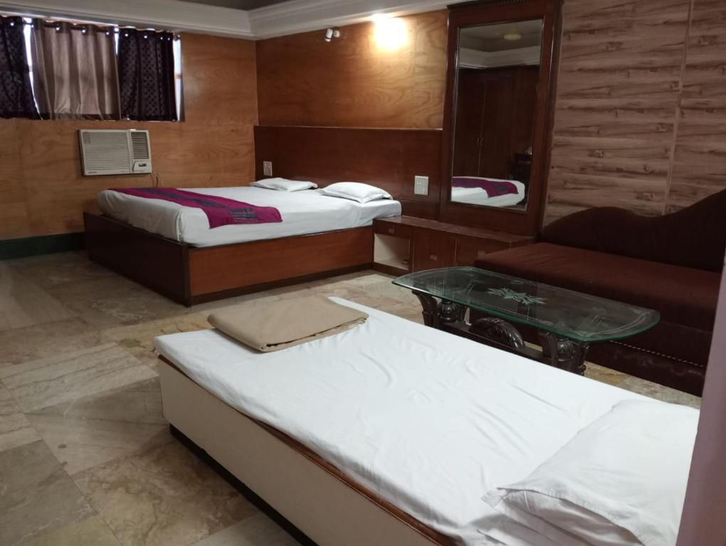 a hotel room with two beds and a couch at Hotel Sun Beam Near Gwalior Railway Station in Gwalior