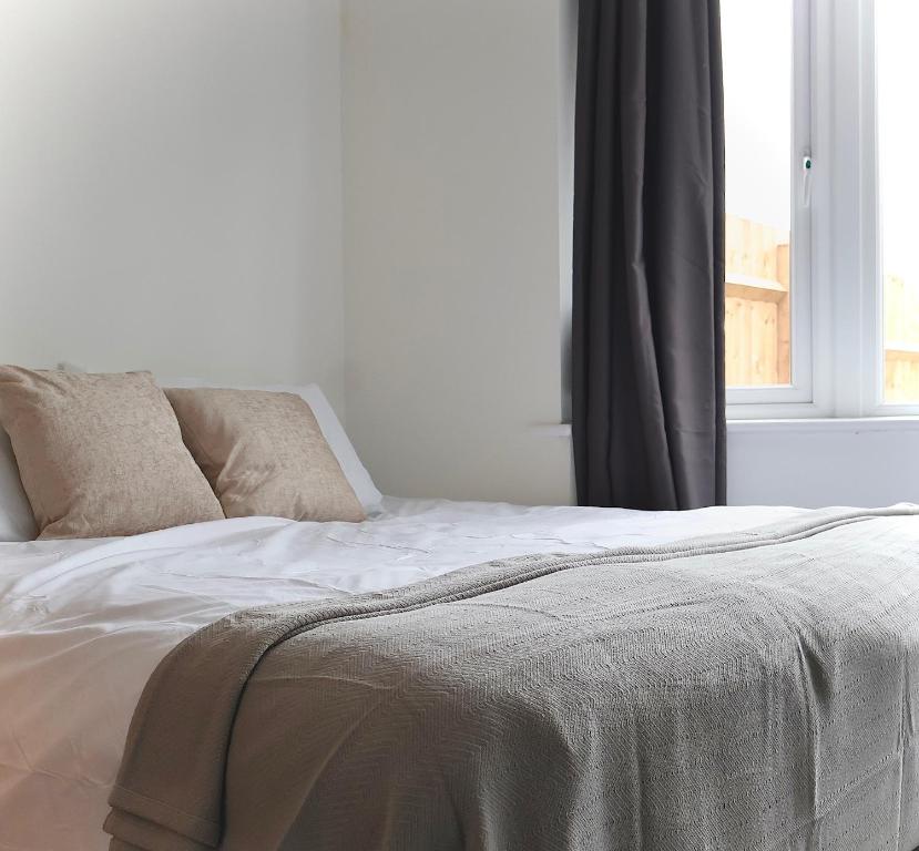białe łóżko z 2 poduszkami i oknem w obiekcie Alban Suites w Saint Albans