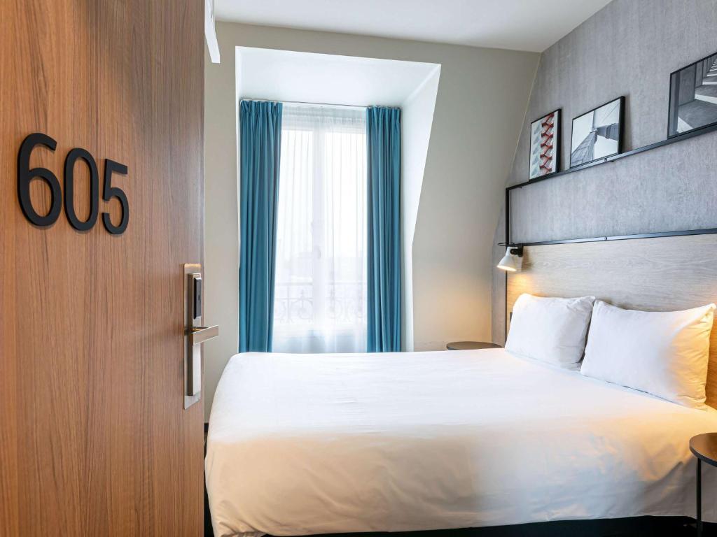 une chambre d'hôtel avec un lit et une fenêtre dans l'établissement ibis Paris Boulogne Billancourt, à Boulogne-Billancourt