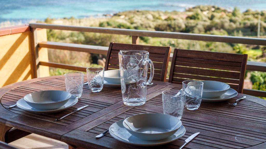 a wooden table with plates and glasses on it at Essenza Di Sardegna in Santa Marinella