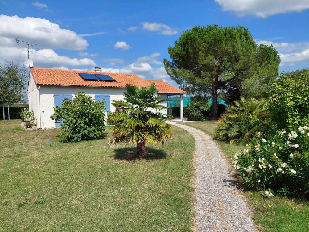 une maison avec un palmier à côté d'un chemin de gravier dans l'établissement lacabaneagigi, à Chaillevette