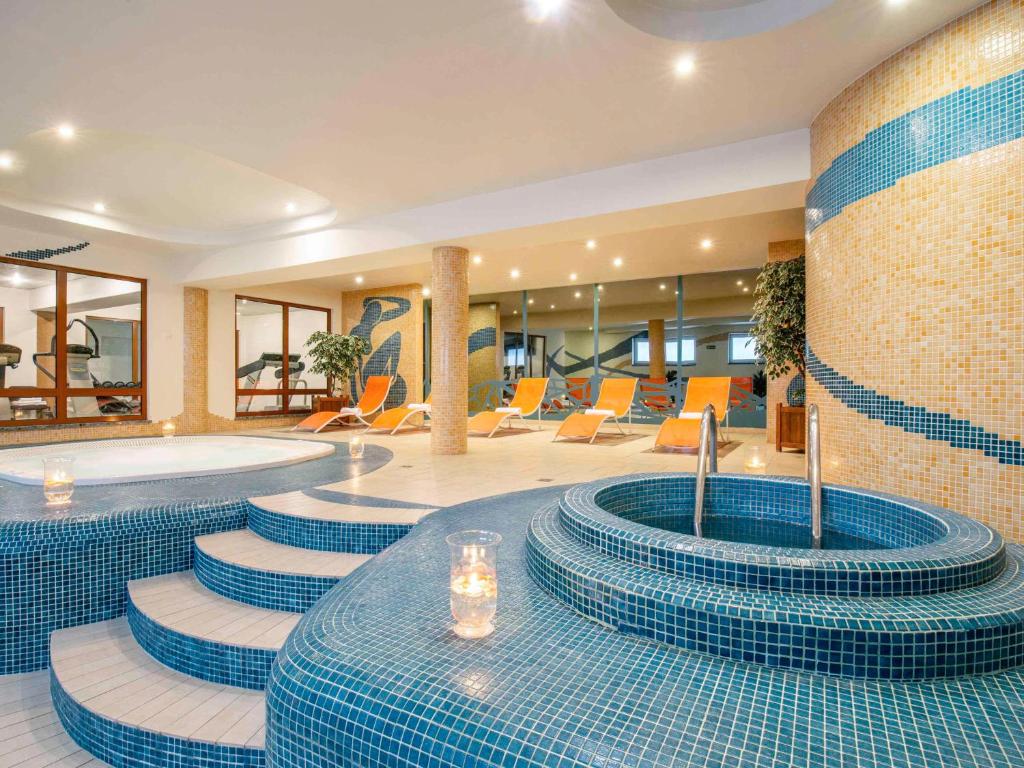 a hotel lobby with blue tiled floors and a swimming pool at ibis Styles Warszawa West in Mory