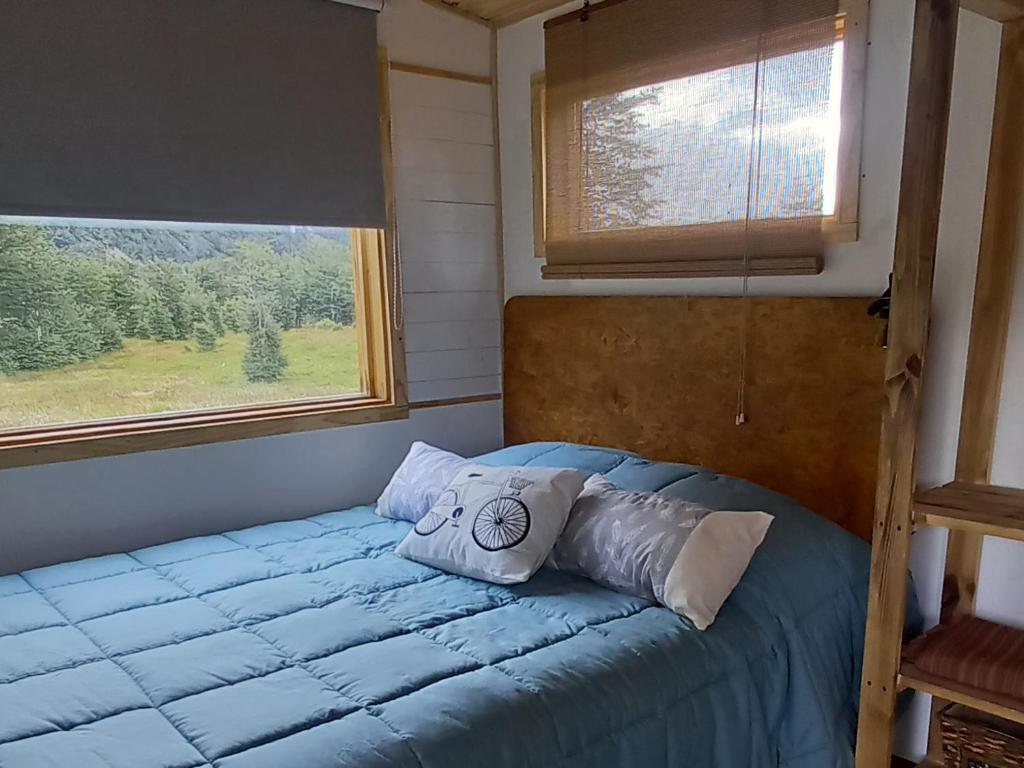 łóżko w pokoju z 2 poduszkami i oknem w obiekcie LA CABAÑA DEL CAMPO w mieście Ushuaia
