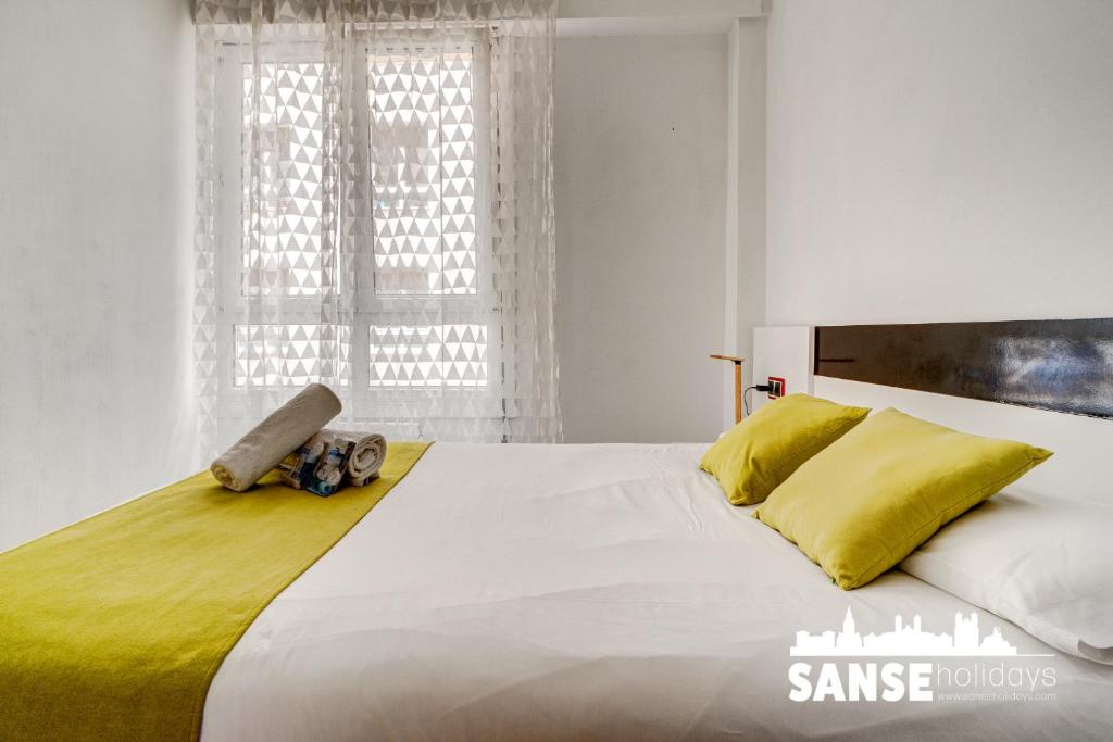 a bedroom with a large white bed with yellow pillows at Apartamento Karri by SanSe Holidays in San Sebastián