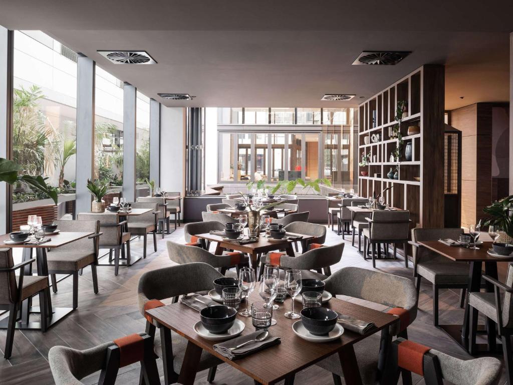 ein Restaurant mit Tischen und Stühlen und großen Fenstern in der Unterkunft Novotel Perth Murray Street in Perth