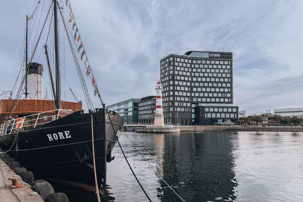 een boot aangemeerd in het water naast een gebouw bij Story Hotel Studio Malmo, part of JdV by Hyatt in Malmö