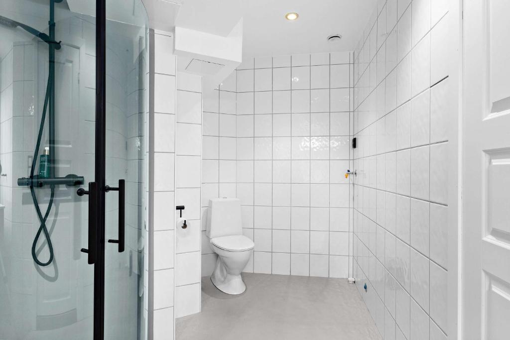 a white tiled bathroom with a toilet and a shower at Ole Bull, Best Western Signature Collection in Bergen