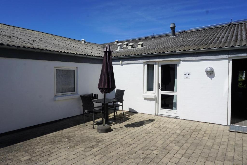 un patio con sombrilla, mesa y sillas en Kerteminde Byferie - Hyrdevej 83, 85K en Kerteminde