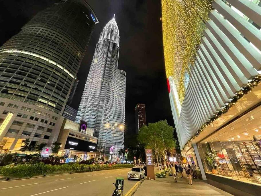 a city street with tall buildings at night at 1 min to KLCC Twin Tower in Kuala Lumpur
