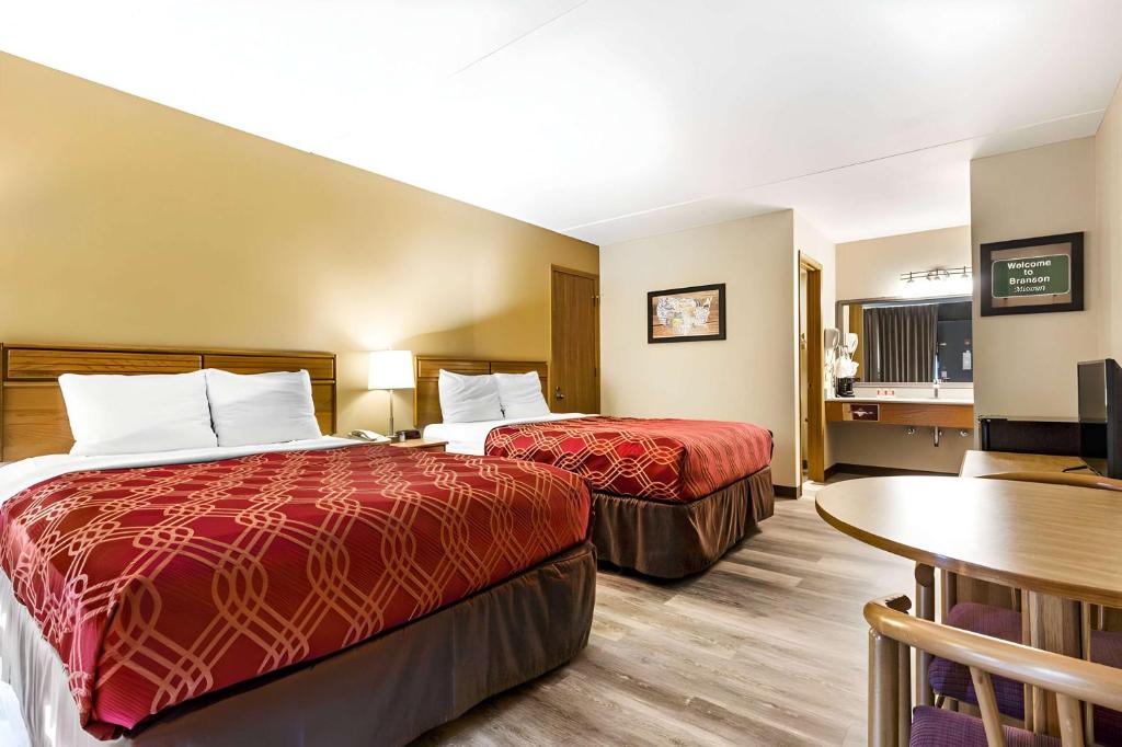 Habitación de hotel con 2 camas y mesa en Ramada by Wyndham Branson Theatre District en Branson