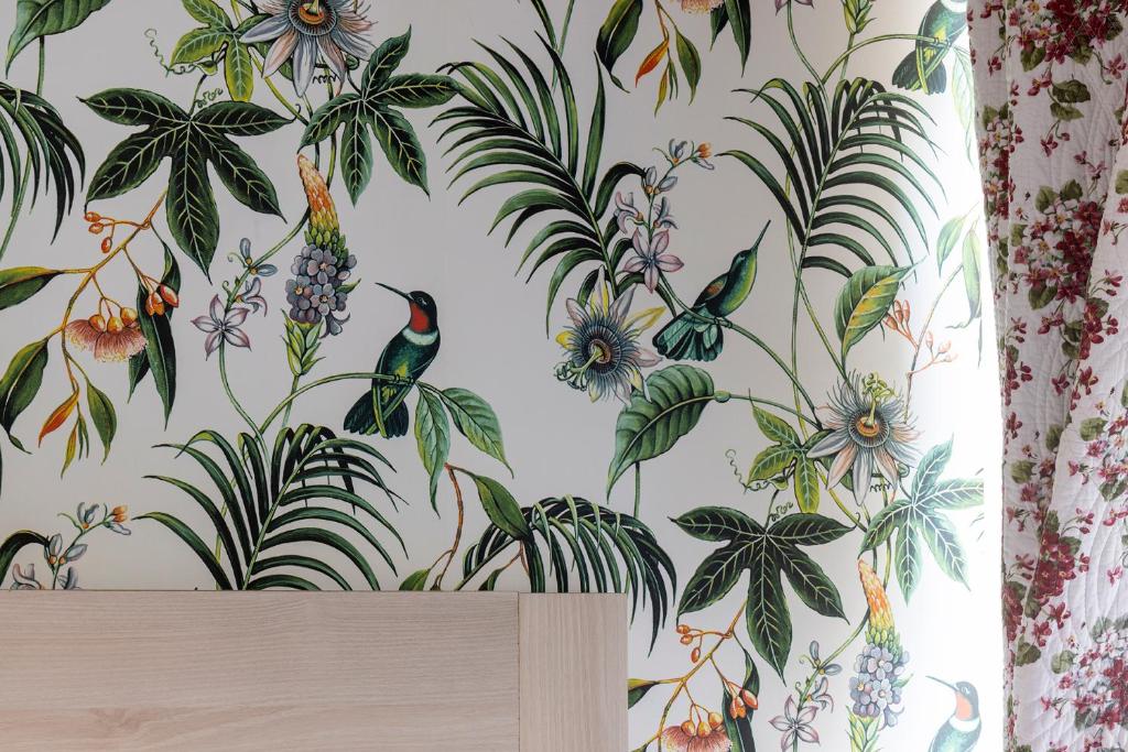 a wallpaper with birds and flowers on a wall at Hôtel de Lion sur Mer in Lion-sur-Mer