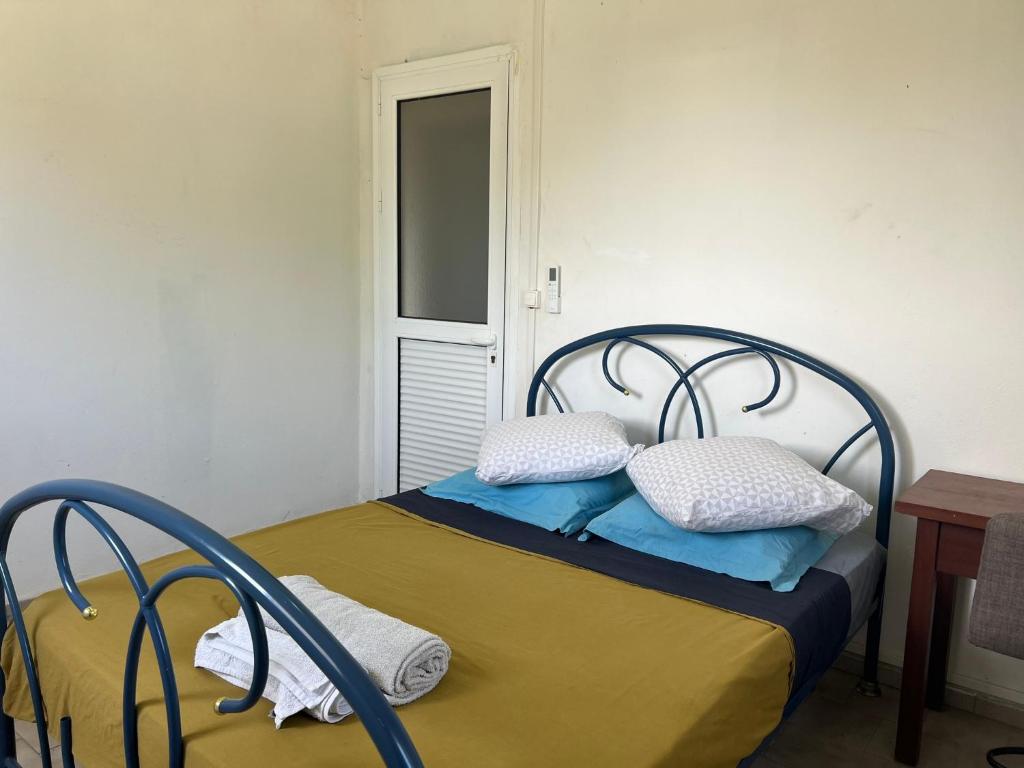 a bedroom with a bed with blue sheets and pillows at CosyLife Sainte-Rose - Villa calme avec vue Sofaïa à 3km de la plage in Sainte-Rose