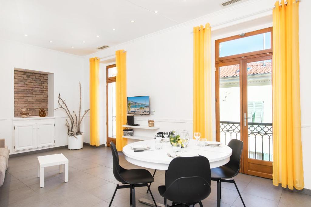 une salle à manger avec une table et des chaises blanches dans l'établissement MARNE III - SPACIEUX 3-4 PIÈCES - Carré d'Or Menton, à Menton