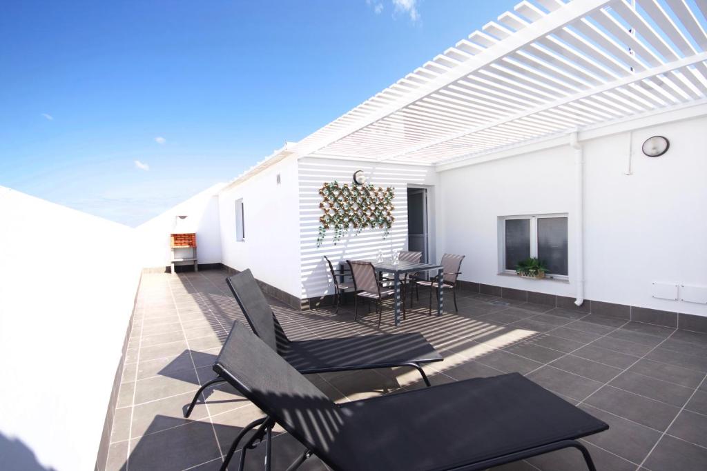 une terrasse avec des chaises et une table ainsi qu'une maison blanche dans l'établissement Apartamentos Las Majoreras 1 y 2 dormitorios, à Las Majoreras