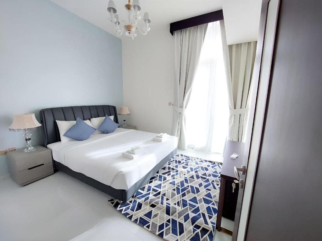 una camera da letto con un letto con cuscini blu e una finestra di Spacious, Economical Apt Near Miralcz Garden a Dubai