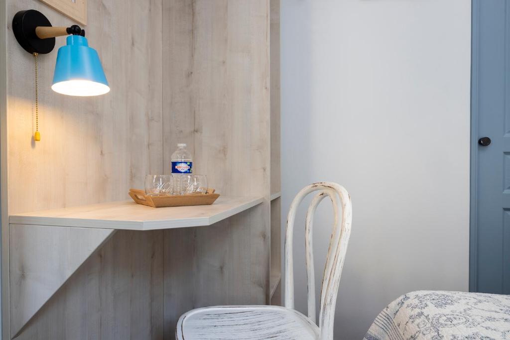 a white chair sitting next to a shelf and a light at Hôtel de Lion sur Mer in Lion-sur-Mer