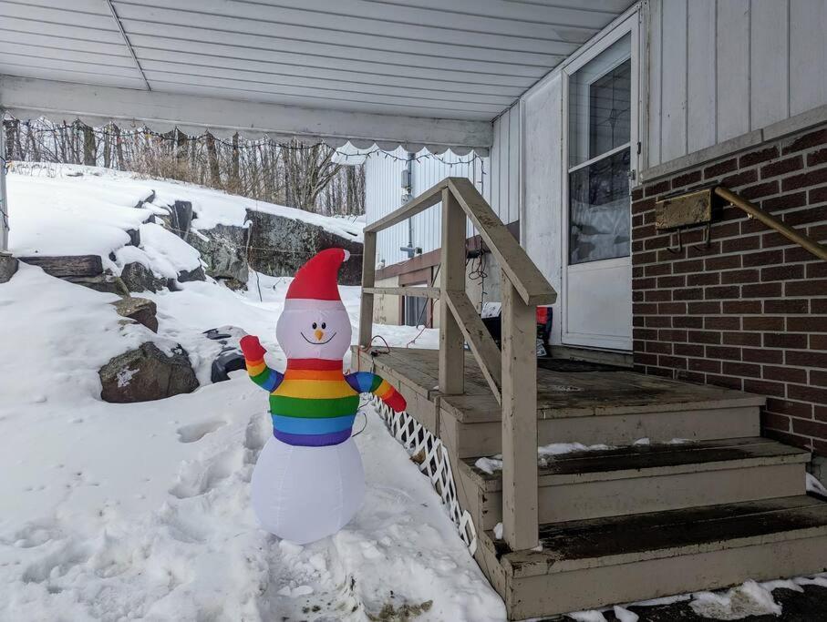 un muñeco de nieve parado frente a una casa en Studio 5 mins to Water in Elliot Lake, Ontario, en Elliot Lake