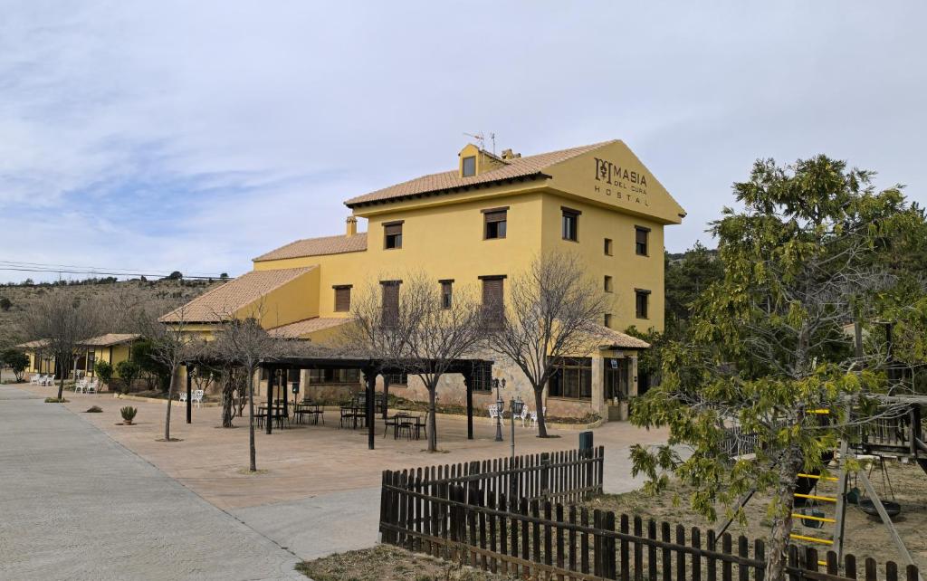 a yellow building with a fence in front of it at Masia Del Cura in Rubielos de Mora
