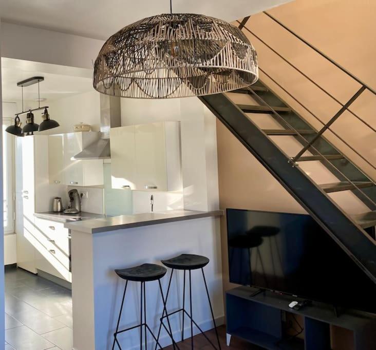 a kitchen with two bar stools and a kitchen with a staircase at La Désirade by Póm in Lorient