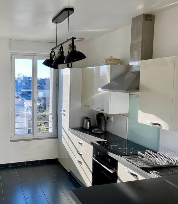 a kitchen with white cabinets and a black stove top oven at La Désirade by Póm in Lorient