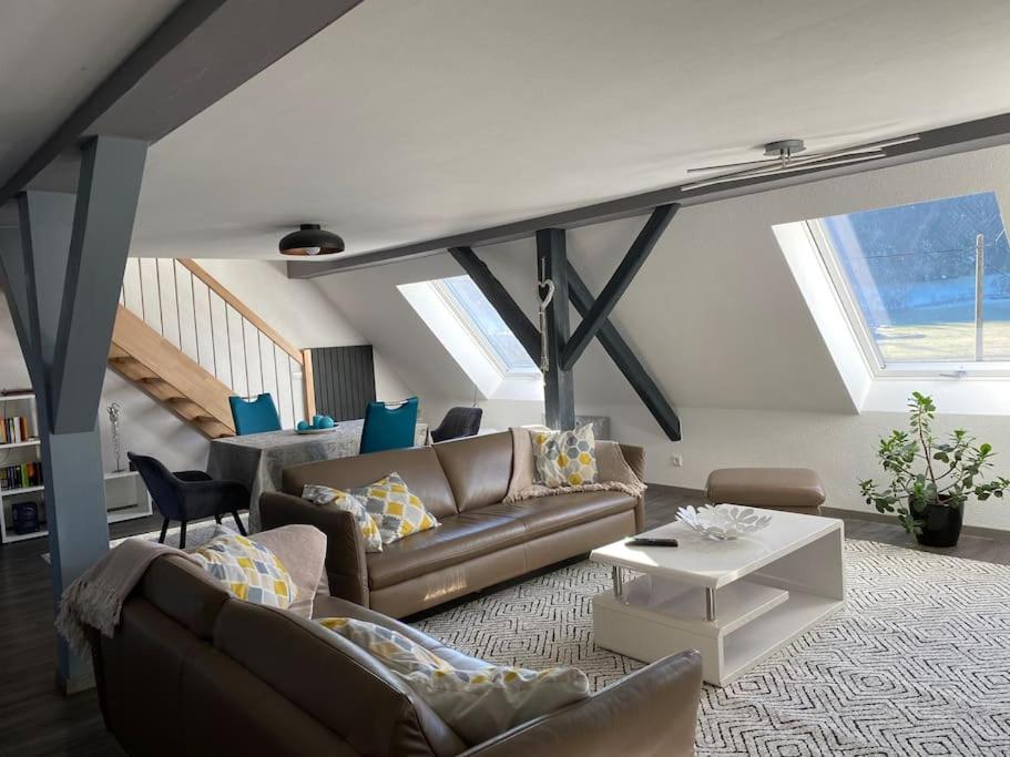 Loft Wohnung mit toller Aussicht في Meßstetten: غرفة معيشة مع أريكة وطاولة