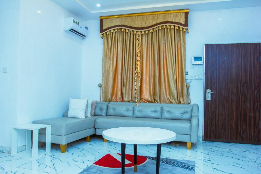 uma sala de estar com um sofá azul e uma mesa em Marathona Service Apartments em Abuja