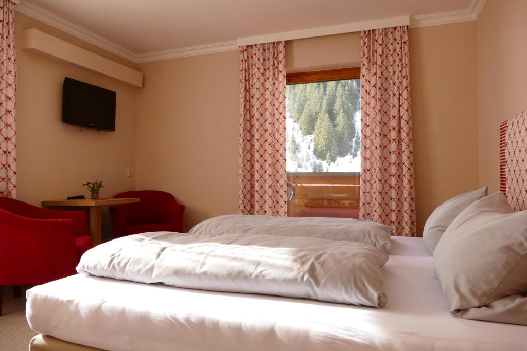 a bedroom with a white bed with a window at Pension DORFPLATZL Pitztal in Plangeross