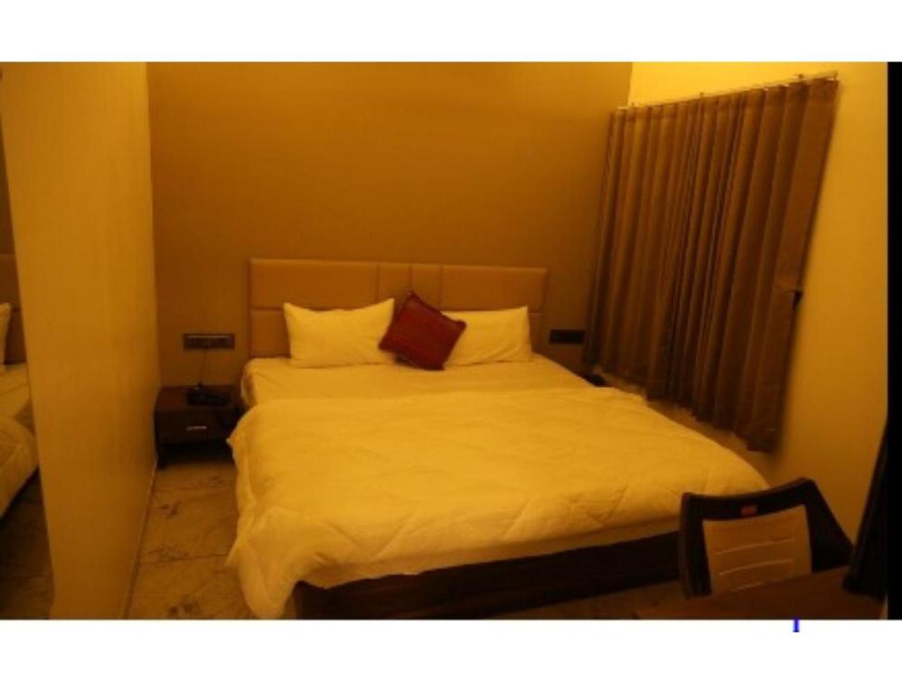 um quarto com uma cama com lençóis brancos e almofadas em Hotel The Pill, Bhavnagar em Bhavnagar