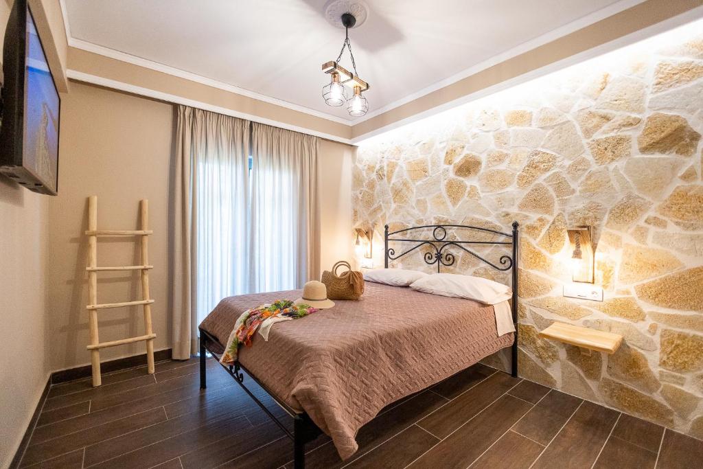 1 dormitorio con 1 cama con pared de piedra en Mathraki Resort en Gouvia